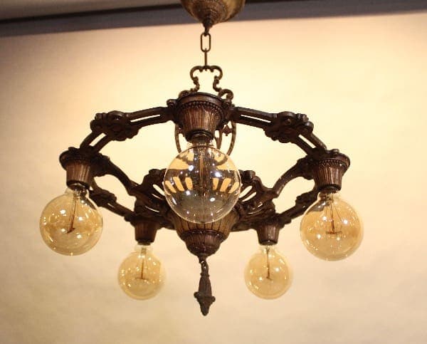Vintage chandelier with five glowing bulbs.