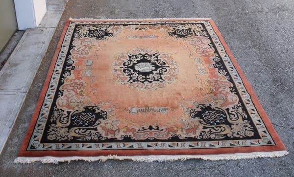 Ornate oriental rug on outdoor pavement.