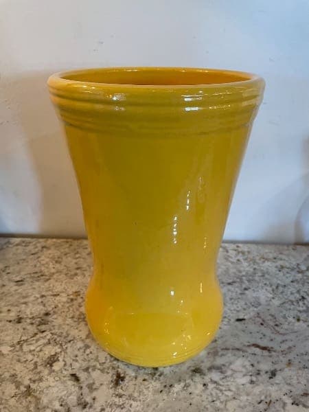 Yellow ceramic vase on speckled countertop.
