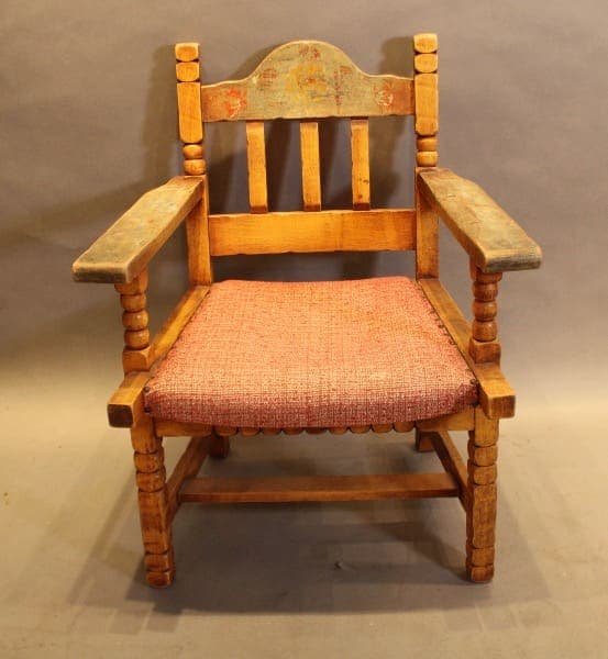 Wooden armchair with red cushioned seat.