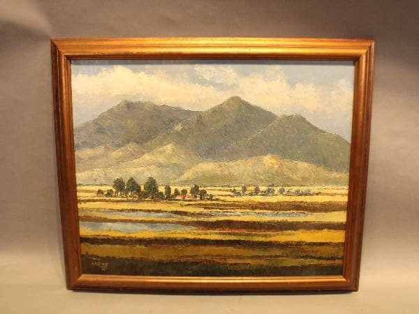 Framed landscape painting with mountains and fields.