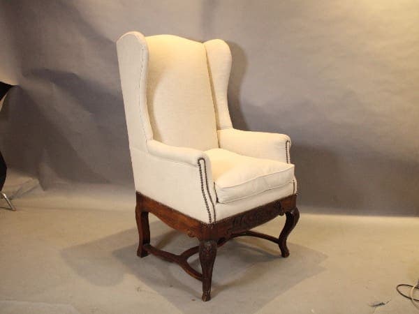 White wingback armchair with wooden legs.