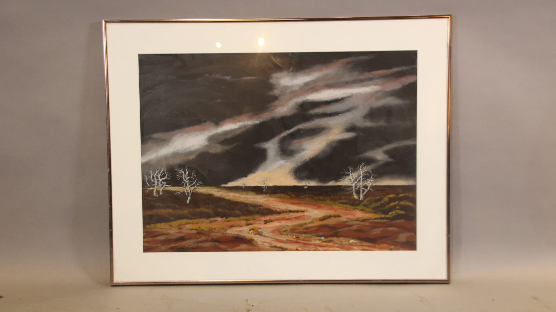 Framed landscape painting with dramatic sky.