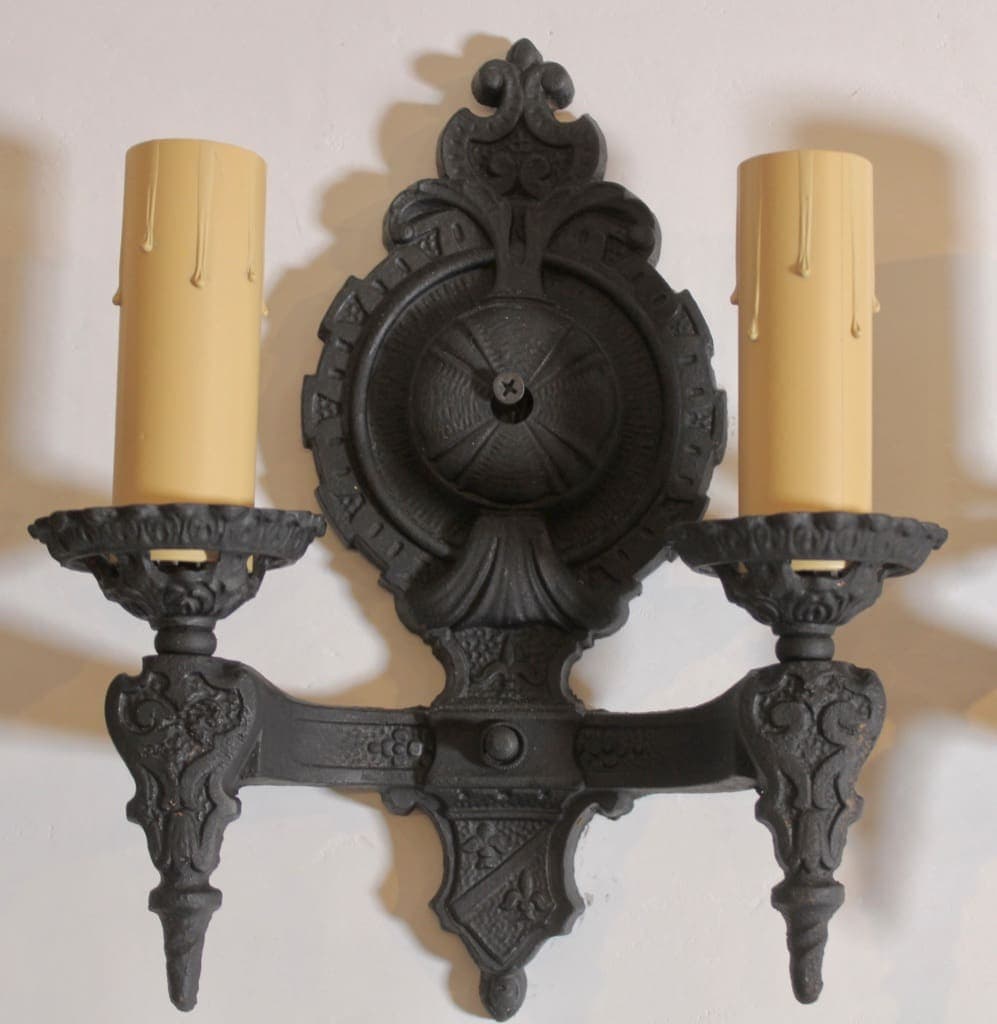 Ornate black wall sconce with two candles