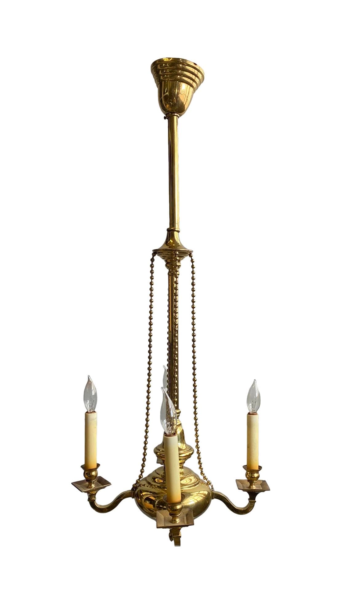 Colonial brass chandelier with four scrolling arms, candlestick sleeves, and beaded chains.
