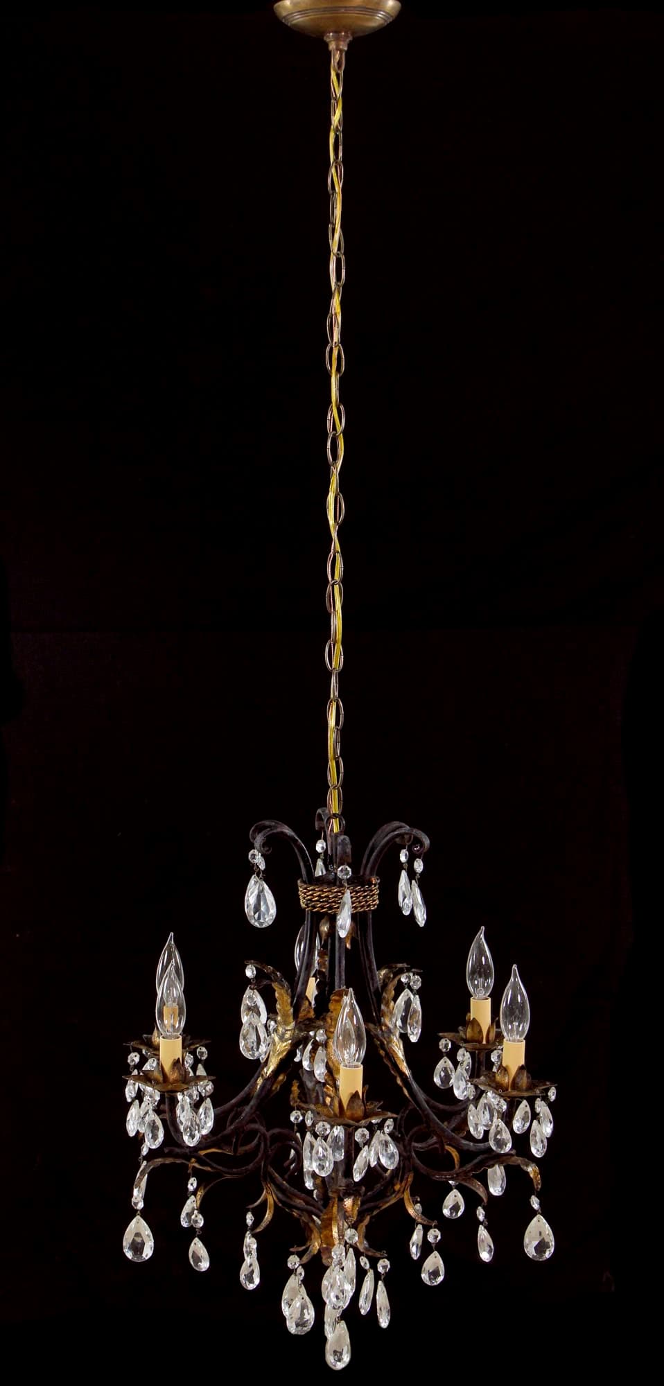 Six-arm chandelier with a black tole frame, gilt foliage accents, and clear crystal drops hanging from each arm and the center.