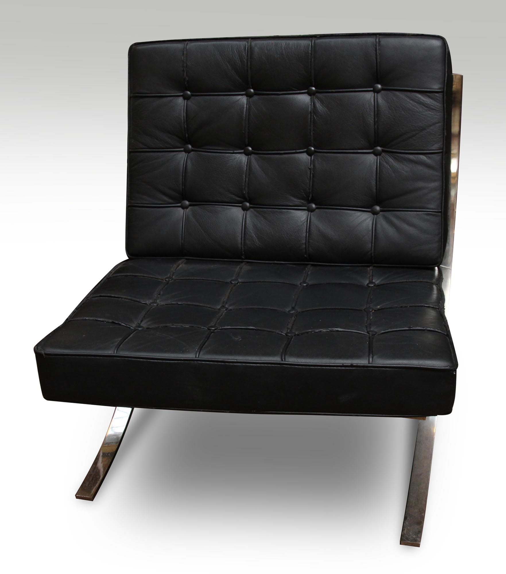 Black leather chair with a tufted back and seat, showing a chrome frame and slight wear with rusted rear legs.